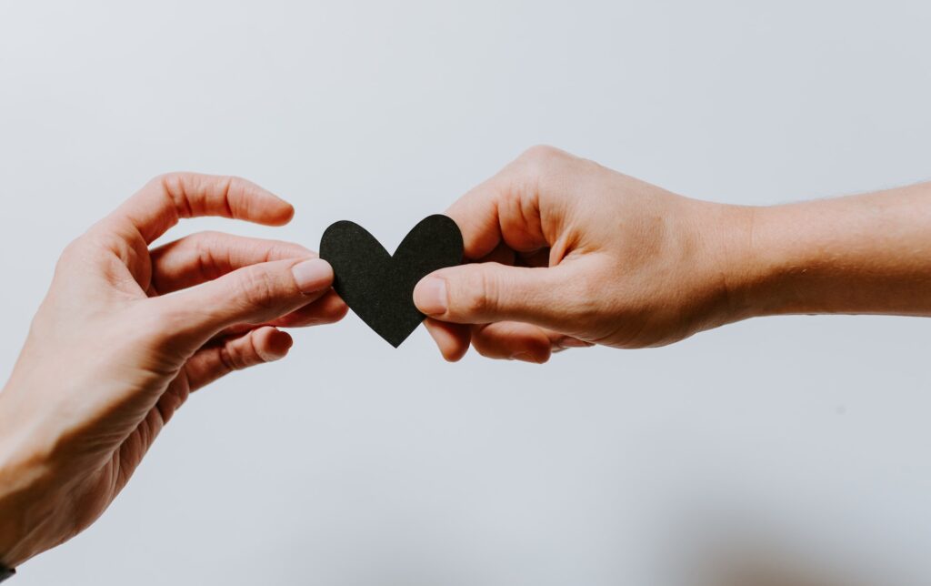 Two people exchanging a heart made out of paper.